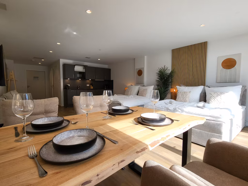 2 Doppelbetten, gedeckter Esstisch und Küche im Deluxe Studio